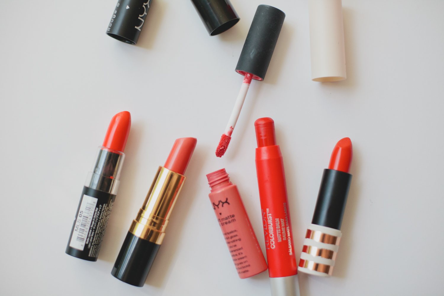 白色桌面上的开架唇膏和唇釉，能看到 NYX、露华浓等平价品牌